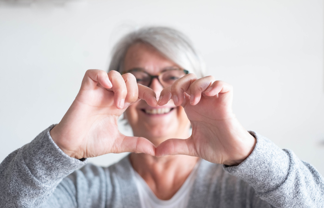 senior white female holds up hands in shape of heart