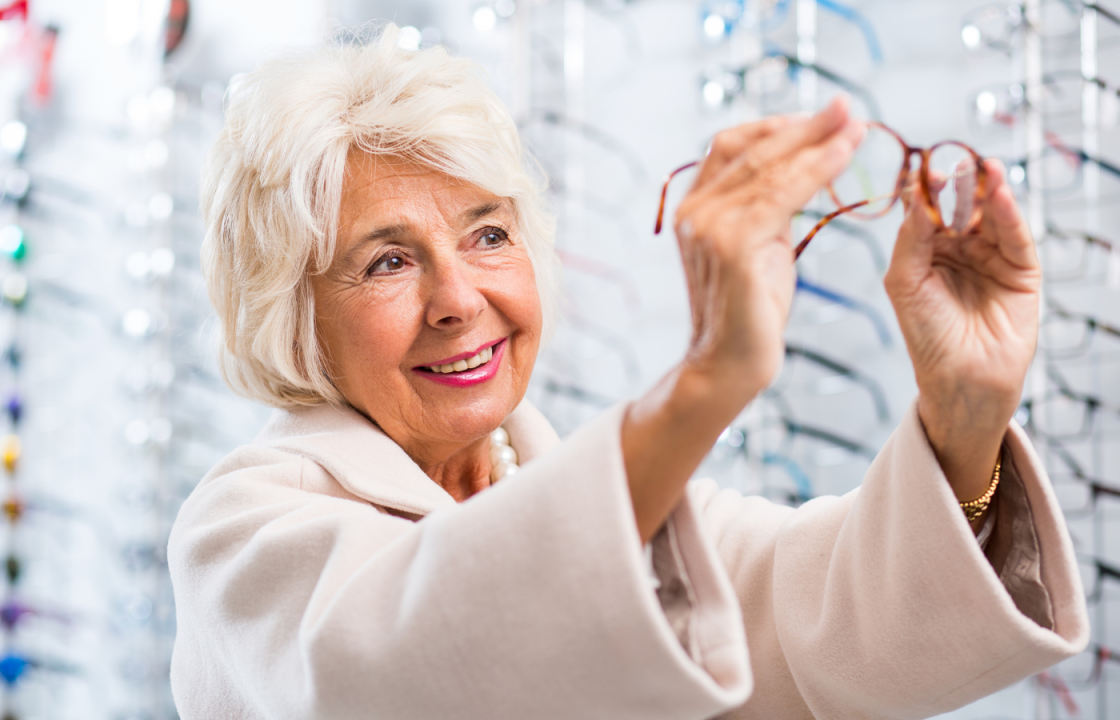 Older white female smiles as she looks up at glasses