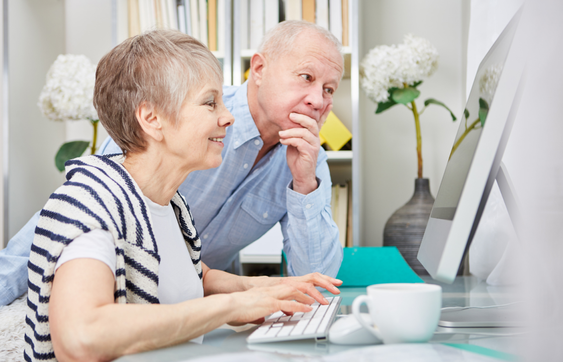 white older husband and wife sitting at computer