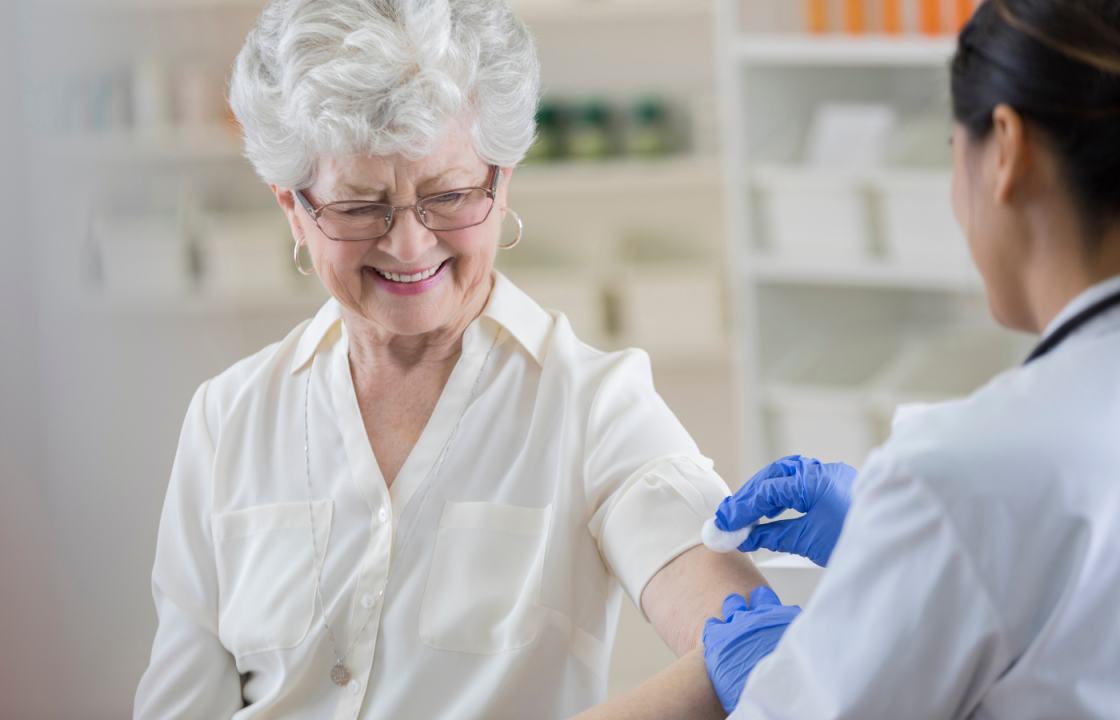 white older woman getting flu shot from female doctor