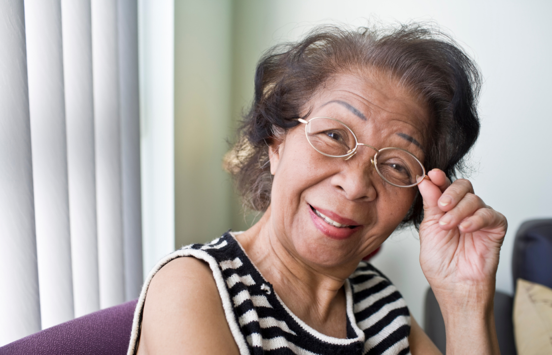 African American older female smiling holding glasses